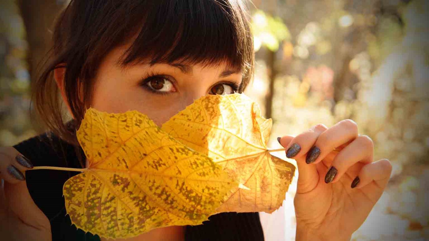 Девушка в осенних листьях с короткой стрижкой